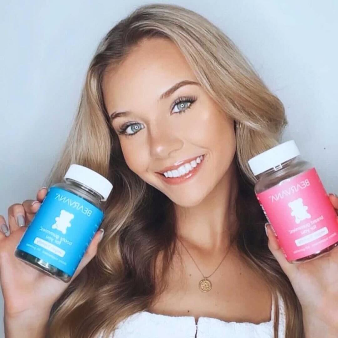 Women’s Support Supplement | Gummies Combo Pack held by a smiling woman, showcasing berry-flavored gummies in blue and pink bottles.