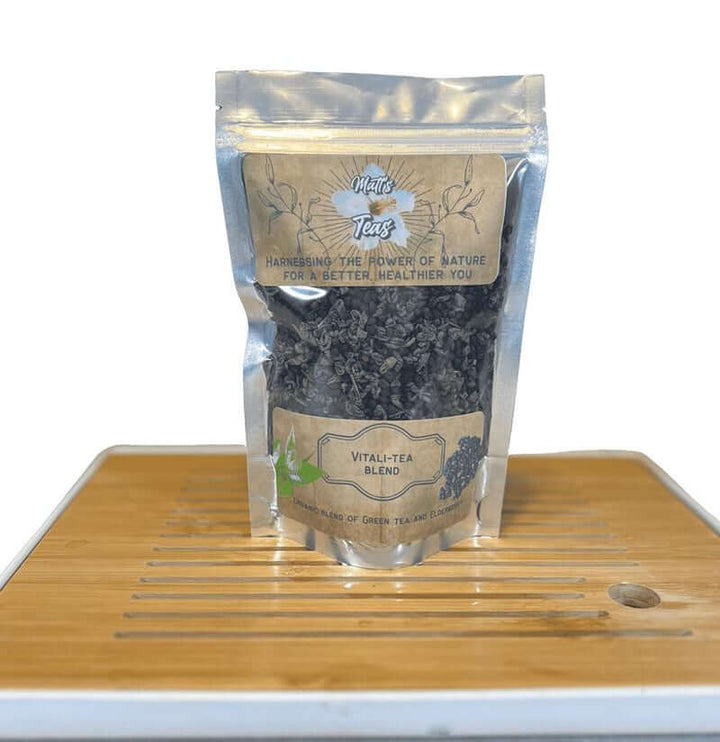 Green Tea and Elderberry Loose Leaf Herbal Tea in a resealable pouch on a bamboo tray.